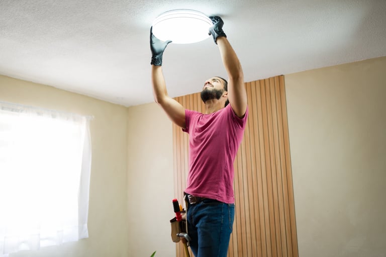 Electrician installing a ceiling light fixture in a modern home
